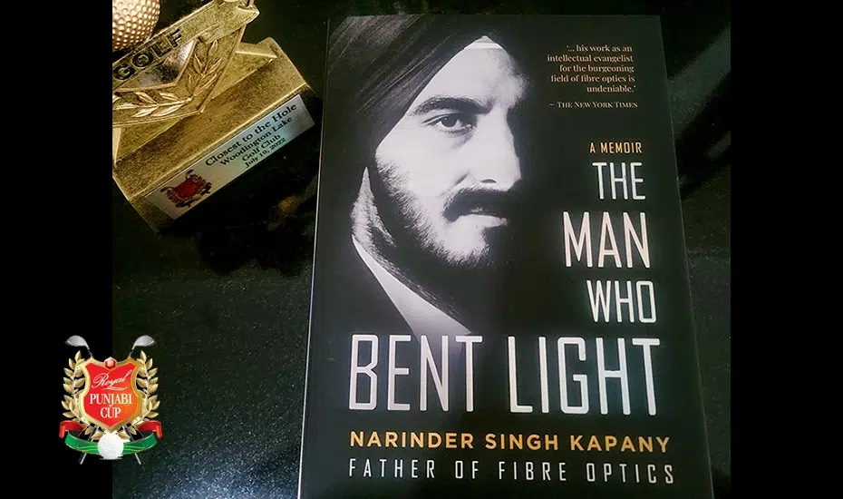 A picture of Narinder S. Kapany's book, "The Man Who Bent Light" atop a black table, commemorating 150 copies donated to Punjabi Golfers Association.